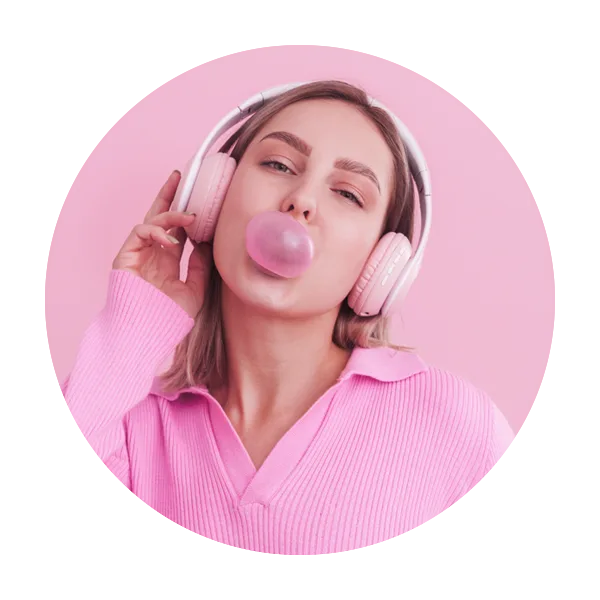 girl with pink headphones and sweater blowing pink bubble gum